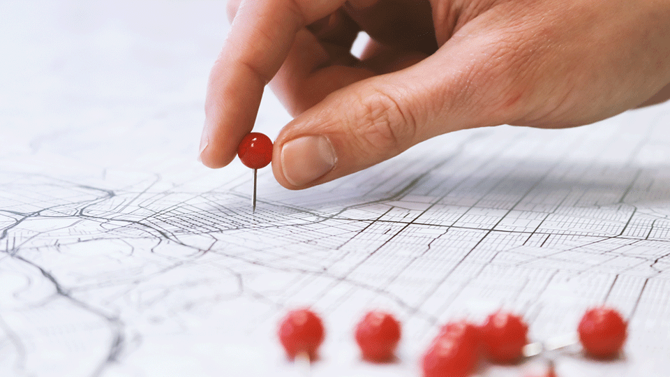 Hand putting pin in map